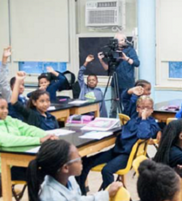 kids in a class room raising their hands