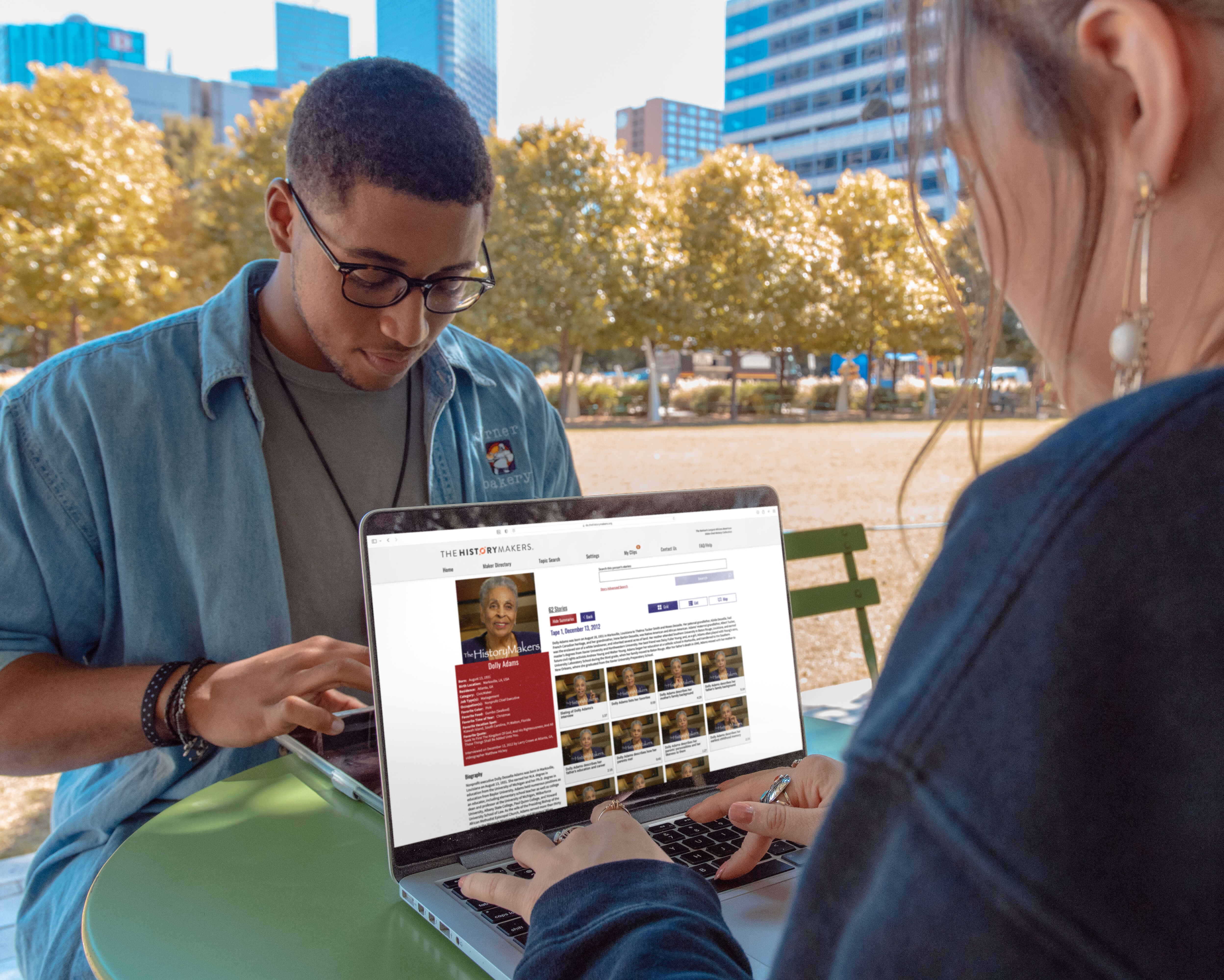 Image of two people outside at a table on their laptops looking at The HistoryMakers Digital Archive